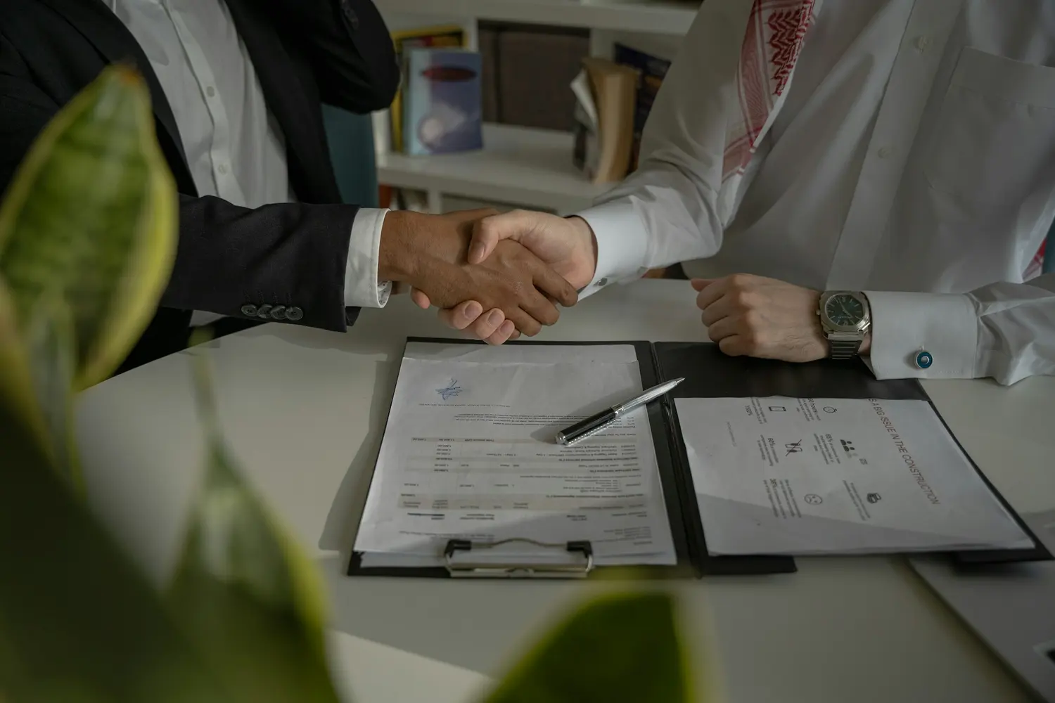 A handshake over signed agreements on a desk